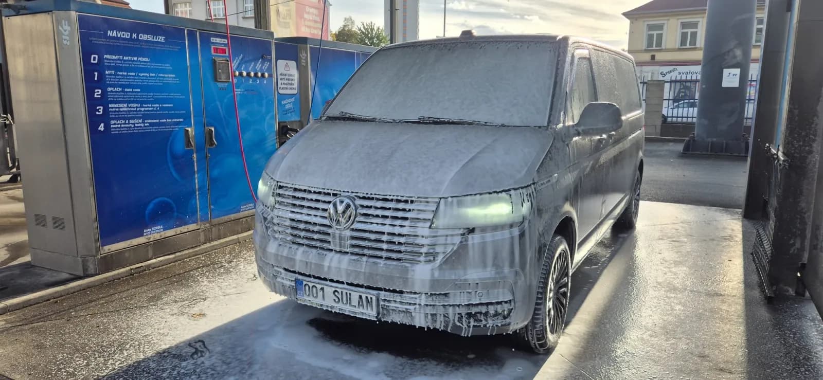 Dodávka pokrytá bohatou pěnou ze sněhového děla v mycím boxu